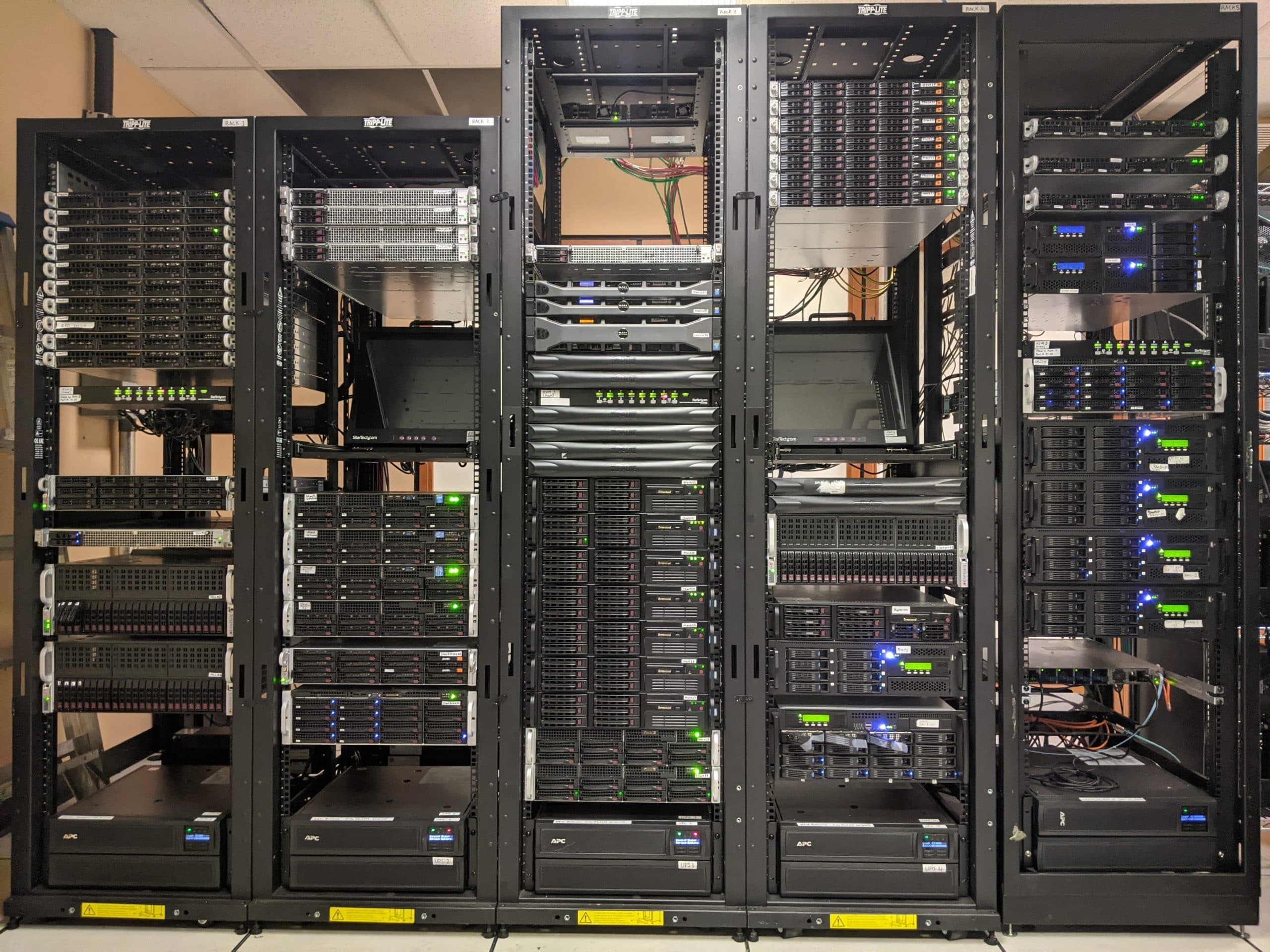 Racks of rack-mounted servers and storage shelves with UPS units at the base.