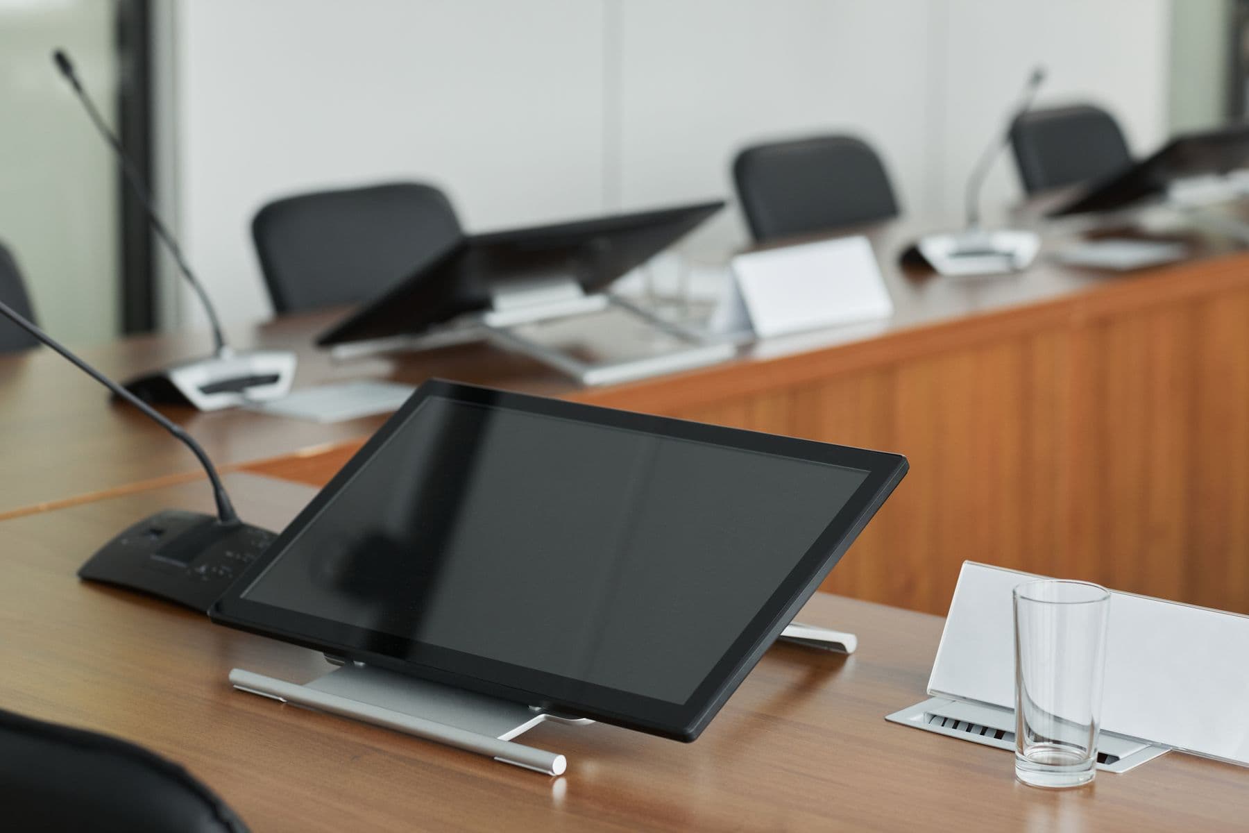 Conference table with a touch display and gooseneck microphones.