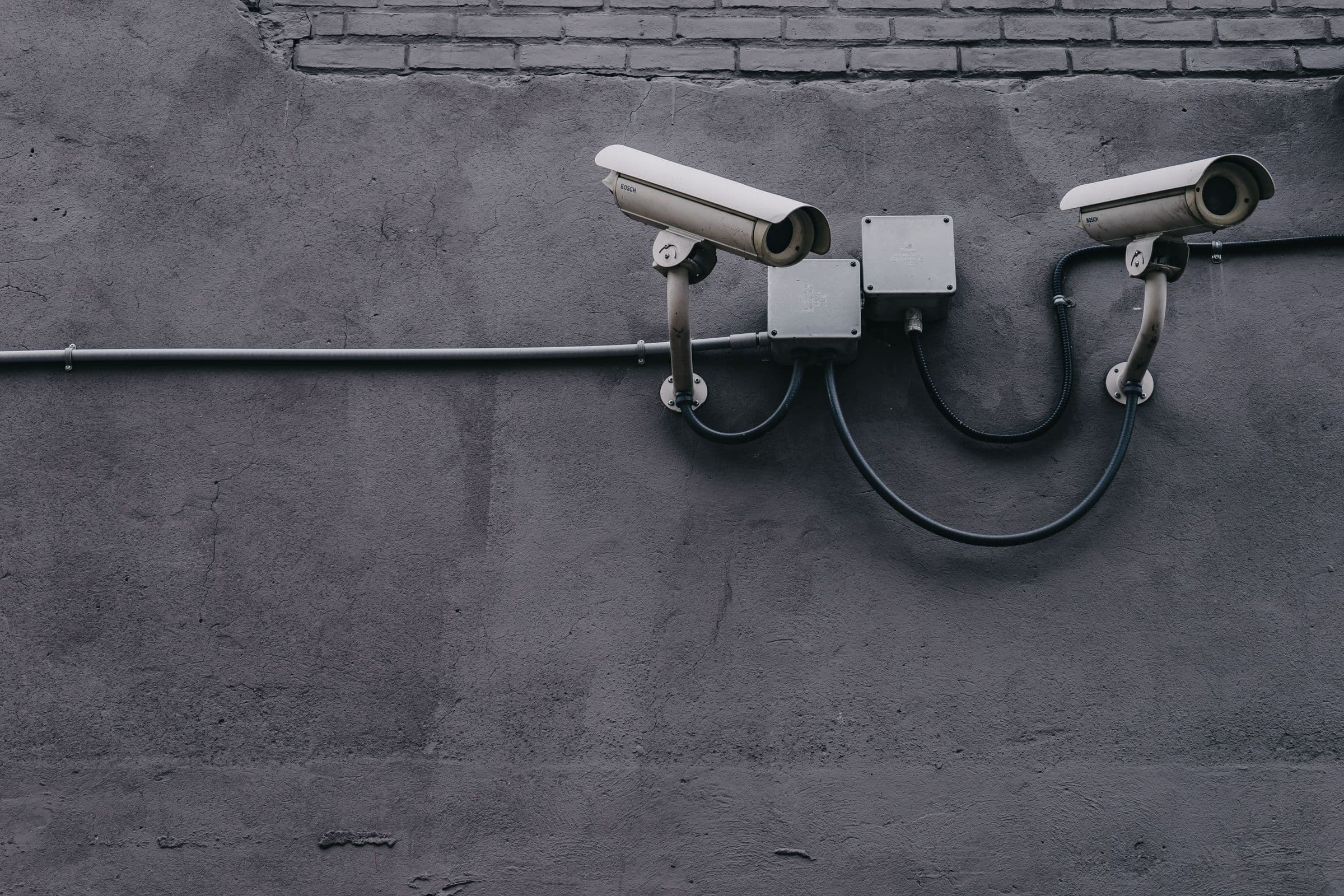 Two surveillance cameras mounted on a concrete wall.
